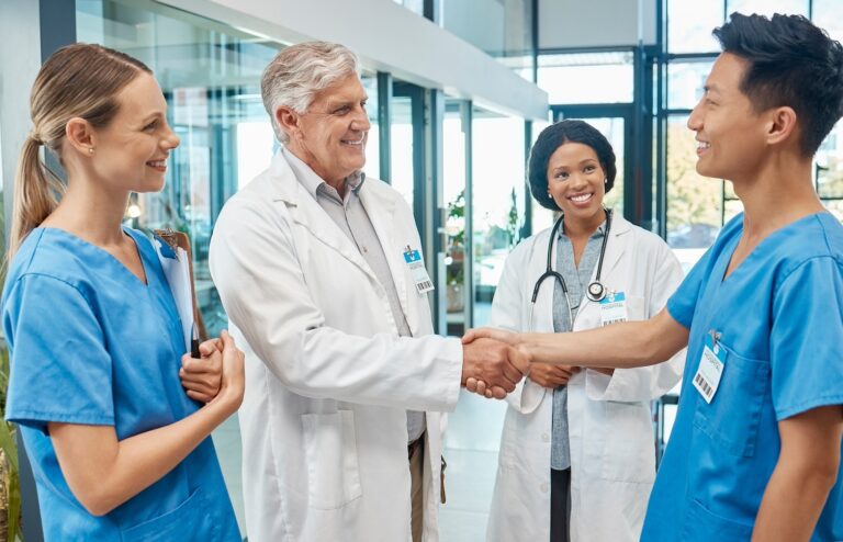 Healthcare, doctor and nurse shaking hands in a hospital to welcome or celebrate success. Men and women medical group together for a handshake, teamwork and collaboration with trust and support.
