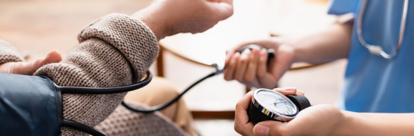 A medical provider holding a blood pressure gauge and taking the blood pressure of a patient
