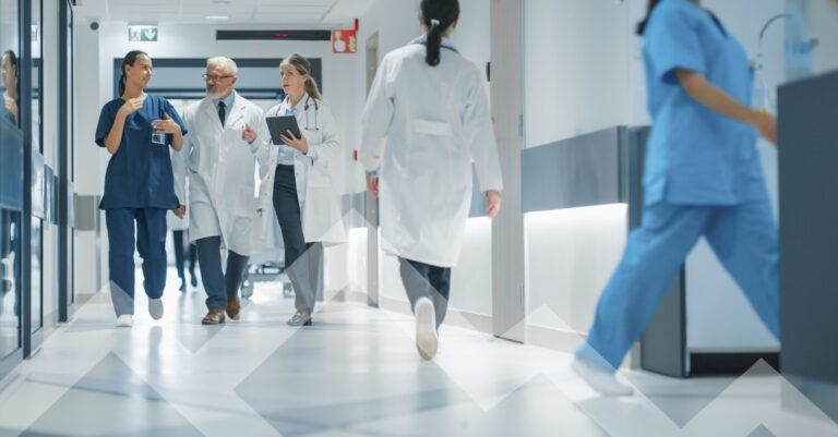 Hospital staff walking and collaborating in a modern hospital hallway, illustrating effective hospital staffing strategies for summer.