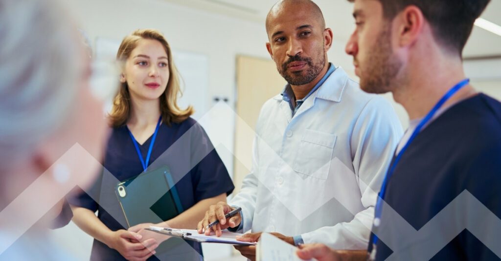 Group of healthcare professionals in discussion, reviewing patient charts and notes in a hospital setting.