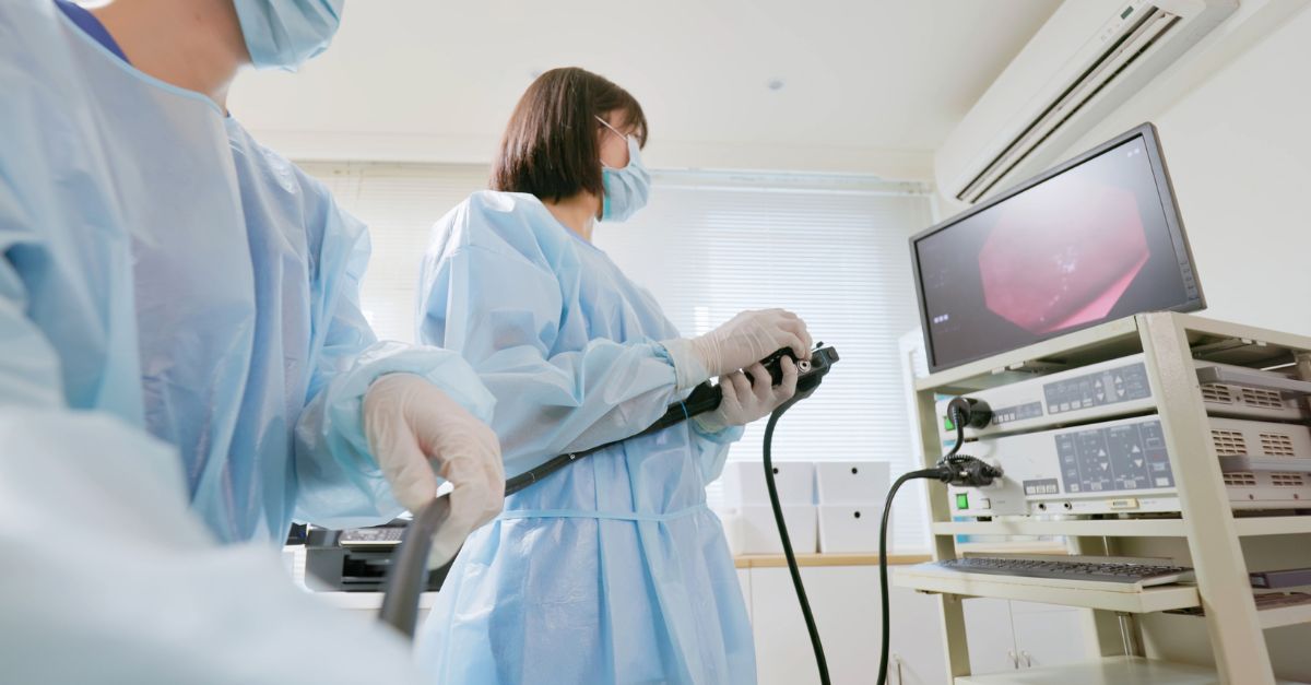 Care team preparing an endoscope with the procedure displayed on a monitor